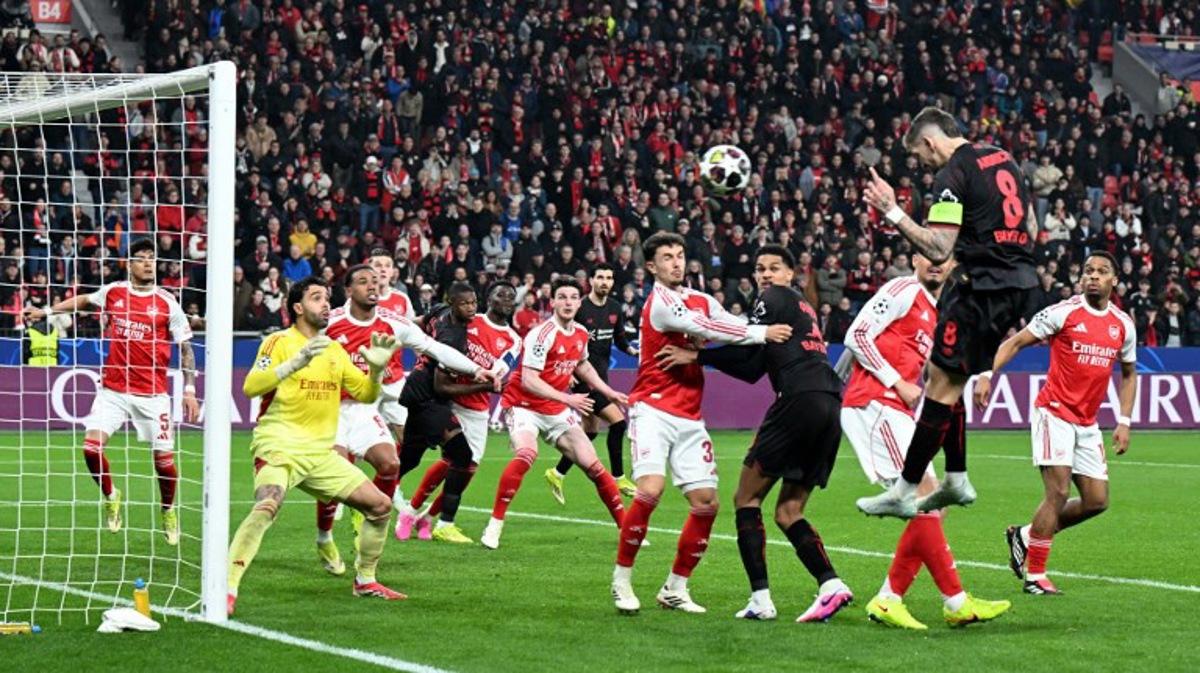 Bayer Leverkusen's German midfielder #08 Robert Andrich (2R) heads the ball to score his team's first goal during the UEFA Champions League, Last 16, first-leg football match Bayer 04 Leverkusen vs Arsenal in Leverkusen, western Germany, on March 11, 2026. UWE KRAFT / AFP