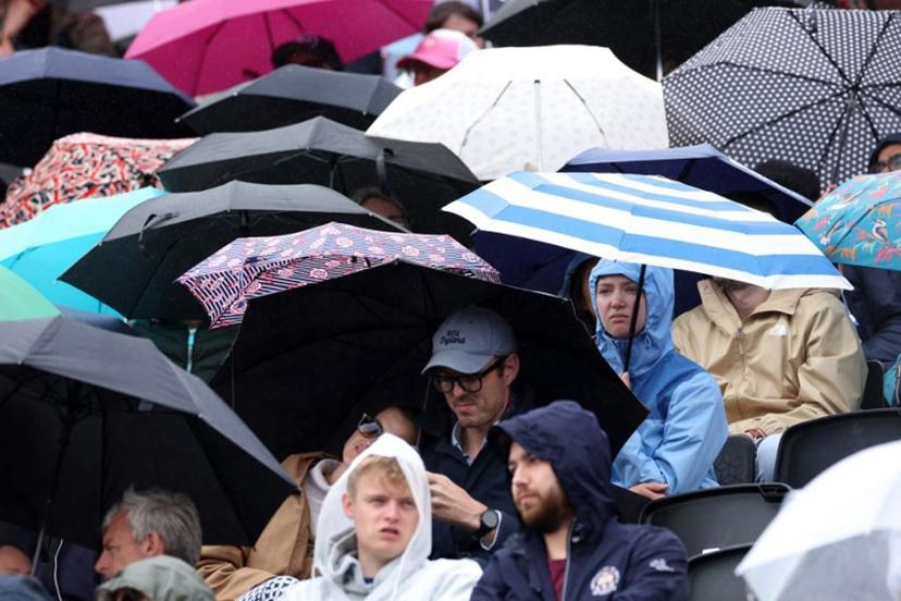People shelter under umbrella's as a rain delay suspends the round of 32, singles match at the HSBC WTA tennis Championships at Queen's Club in west London on June 8, 2026. Adrian Dennis / AFP