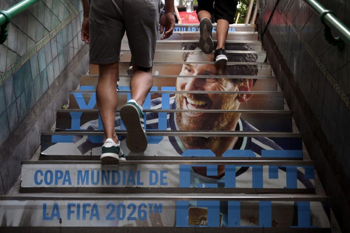 People leave a subway station with an advertising of Argentina´s National football team jersey and the portrait of Argentina's forward Lionel Messi in Buenos Aires on February 24, 2026. JUAN MABROMATA / AFP
