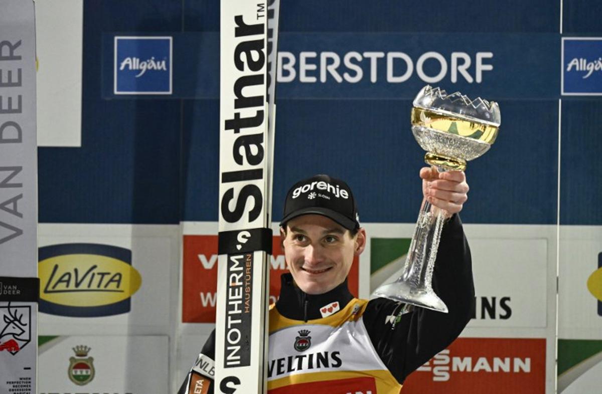 Winner, Slovenia's Domen Prevc, celebrates on the podium with his trophy after the second jump of the Men's Individual Large Hill HS137 event of the FIS Ski Jumping World Cup, the first leg of the Four Hills Tournament, in Oberstdorf, southern Germany on December 29, 2025. PHILIPP GUELLAND / AFP