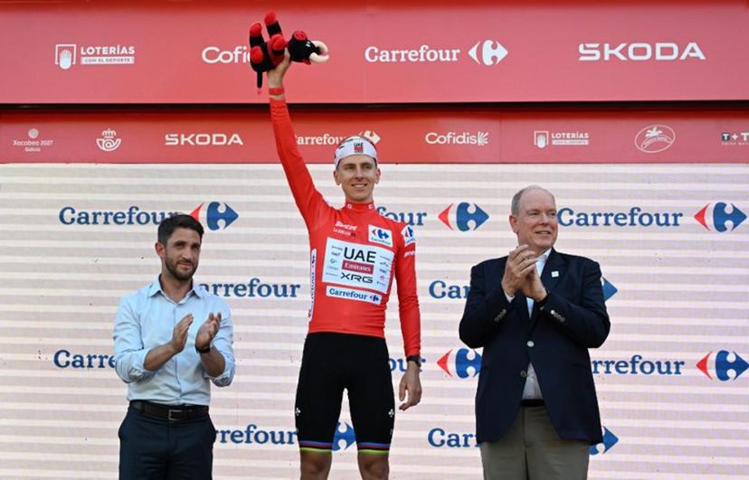 UAE Team Emirates - XRG team's Slovenian rider Tadej Pogacar celebrates on the podium wearing the overall leader's red jersey flanked by Prince's Albert II of Monaco (R) and Manosque's mayor Camille Galtier after the second stage of the Vuelta a Espana 2026, a 214,3 km race between Monaco and Manosque on August 23, 2026. Miguel MEDINA / AFP