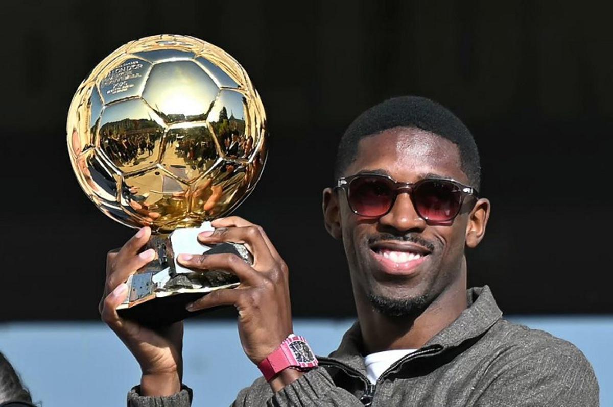 Paris Saint-Germain's French forward Ousmane Dembele holds the 2025 Ballon d'Or trophy during a presentation ceremony at the City Hall in Evreux, his hometown and where he started playing club football, on October 12, 2025. LOU BENOIST / AFP