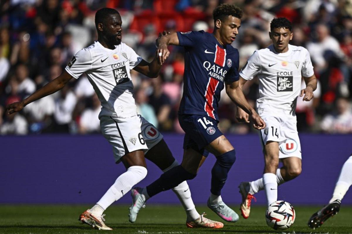 Paris Saint-Germain's French midfielder #14 Desire Doue fights for the ball with Angers' Ivorian midfielder #06 Jean-Eudes Aholou during the French L1 football match between Paris Saint-Germain (PSG) and SCO Angers at The Parc des Princes Stadium in Paris on April 5, 2025. JULIEN DE ROSA / AFP