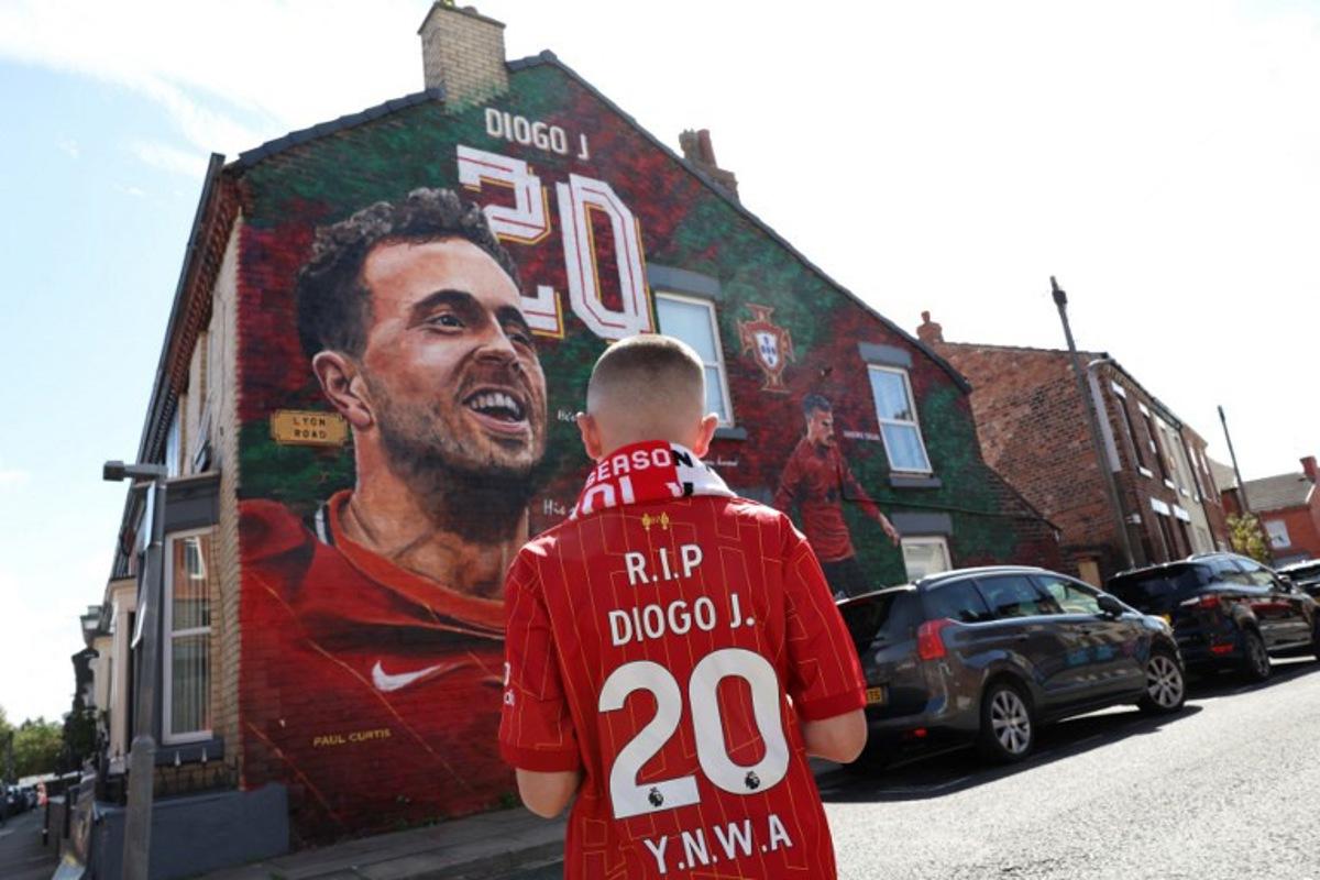 A fan stands in front of a mural by artist Paul Curtis, of Liverpool's late Portuguese striker Diogo Jota and his brother Andre Silva before the first of two pre season friendly football matches between Liverpool and Athletic Bilbao, near Anfield in Liverpool, north west England on August 4, 2025. Darren Staples / AFP