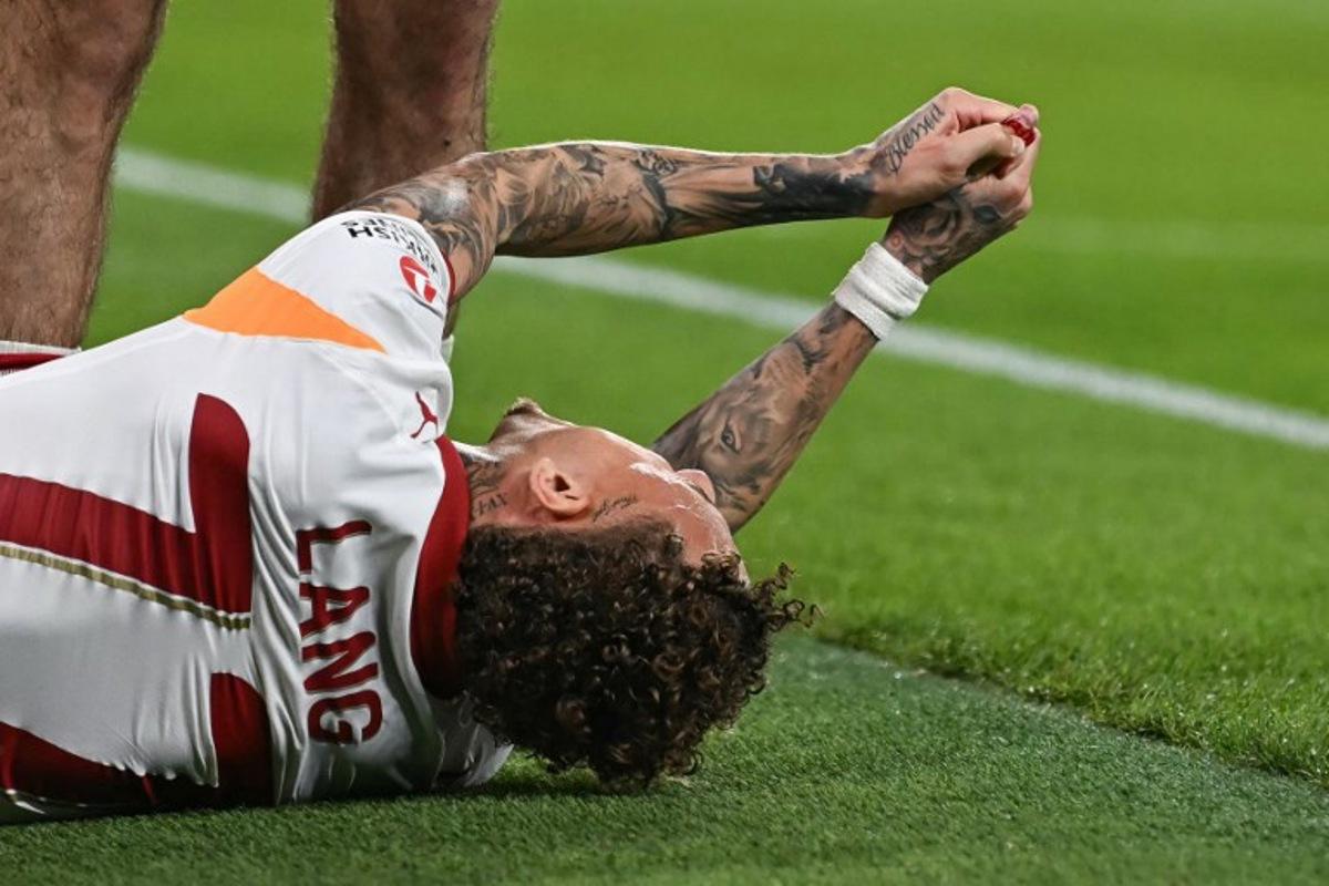 Galatasaray's Dutch forward #77 Noa Lang reacts on the floor after cutting his thumb during the UEFA Champions League, round of 16 second leg football match between Liverpool and Galatasaray at Anfield in Liverpool, north-west England on March 18, 2026. Paul ELLIS / AFP