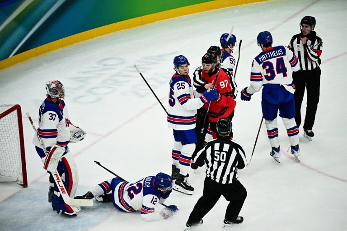 USA's #12 Matt Boldy (down) reacts after a scuffle with Canada's #97 Connor McDavid (4th R) during the men's gold medal ice hockey match between Canada and USA at the Milano Santagiulia Ice Hockey Arena during the Milano Cortina 2026 Winter Olympic Games in Milan, on February 22, 2026. JULIEN DE ROSA / AFP