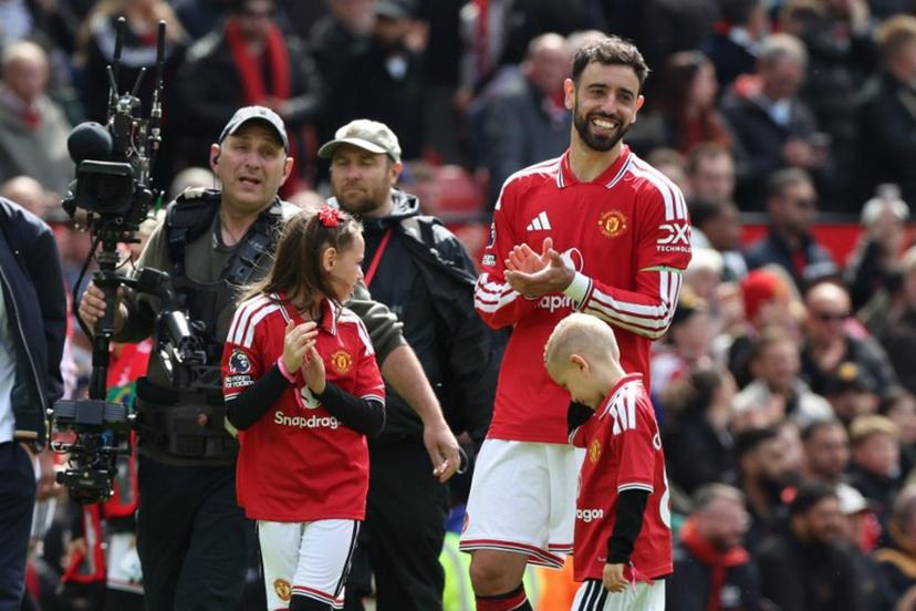 Manchester United's Portuguese midfielder #08 Bruno Fernandes (R) smiles on the pitch after their final home appearance in the English Premier League football match between Manchester United and Nottingham Forest at Old Trafford in Manchester, north west England, on May 17, 2026. United won the game 3-2. Darren Staples / AFP