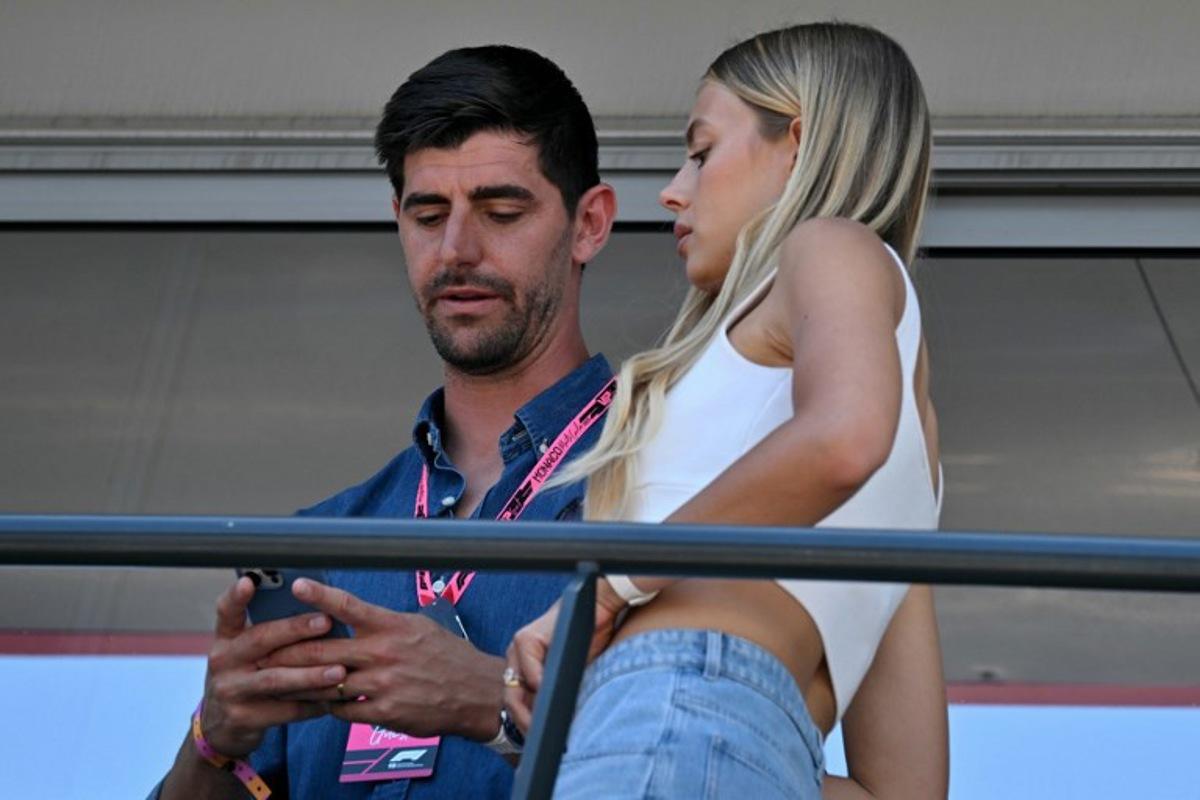 Belgian goalkeeper Thibaut Courtois (L) and wife Mishel Gerzig look at a mobile phone on a balcony ahead of the Formula One Monaco Grand Prix at the Circuit de Monaco, on May 25, 2025. Andrej ISAKOVIC / AFP