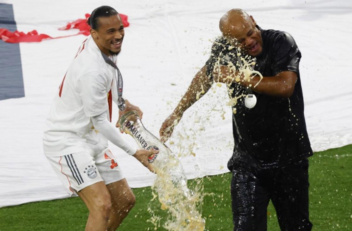 Bayern Munich's Belgian head coach Vincent Kompany is doused with beer by Bayern Munich's German forward #10 Leroy Sane (L) after the German first division Bundesliga football match between Bayern Munich and Borussia Moenchengladbach in Munich on May 10, 2025. Michaela STACHE / AFP